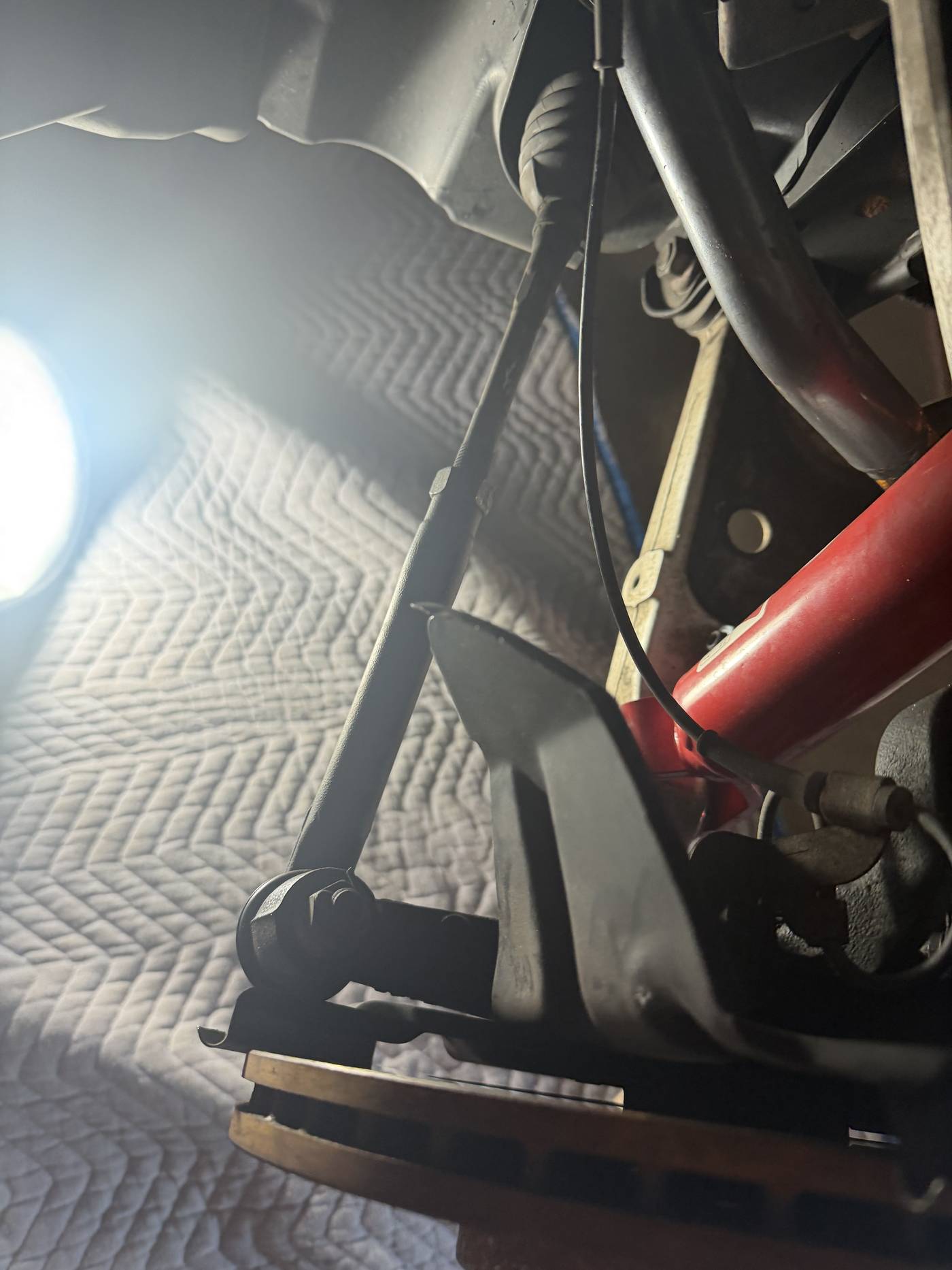 Close-up of a cowl mounting screw sealed with a heavy application of black sealant on the Miata's windshield cowl