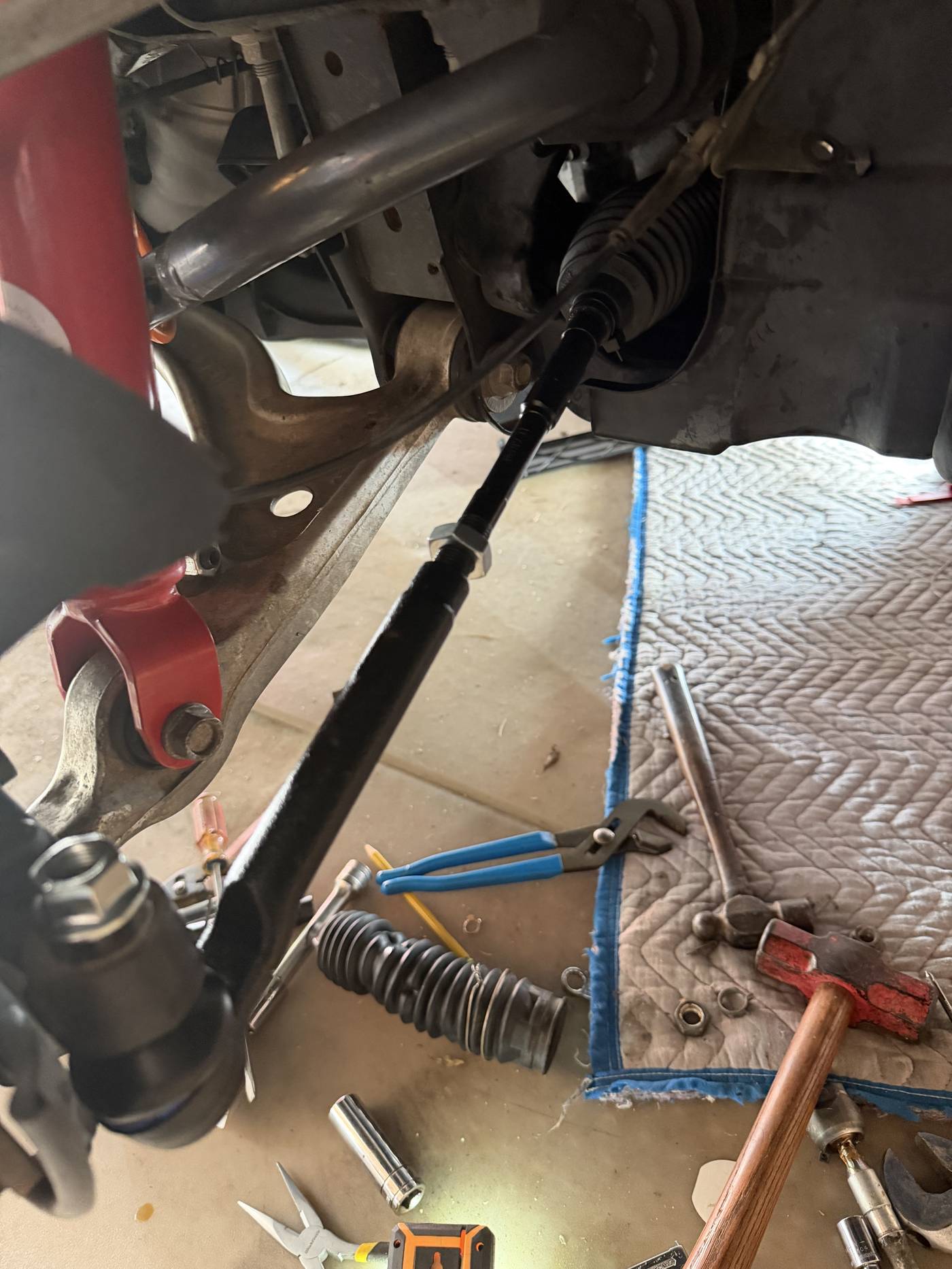 Close-up of a cowl mounting screw sealed with a heavy application of black sealant on the Miata's windshield cowl